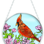 A vibrant red cardinal perched on a branch with pink blossoms.